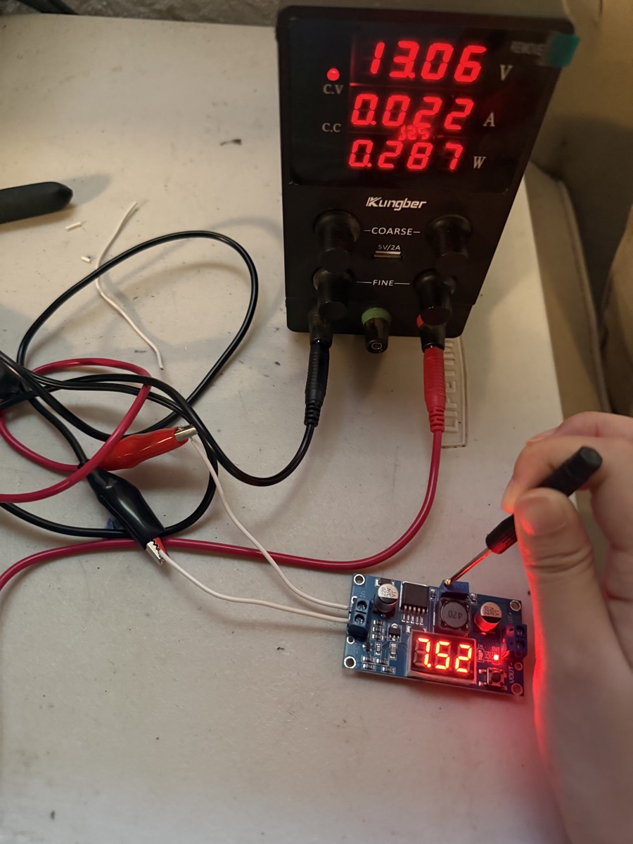 A bench power supply set to 13.06V feeding the buck converter, whose display reads 3.52V while a screwdriver turns the trimpot